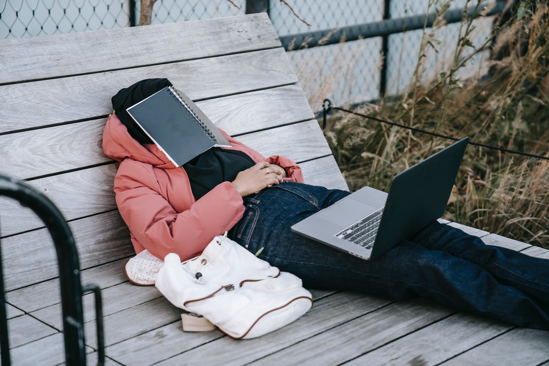 unrecognizable woman with laptop resting on bench in park